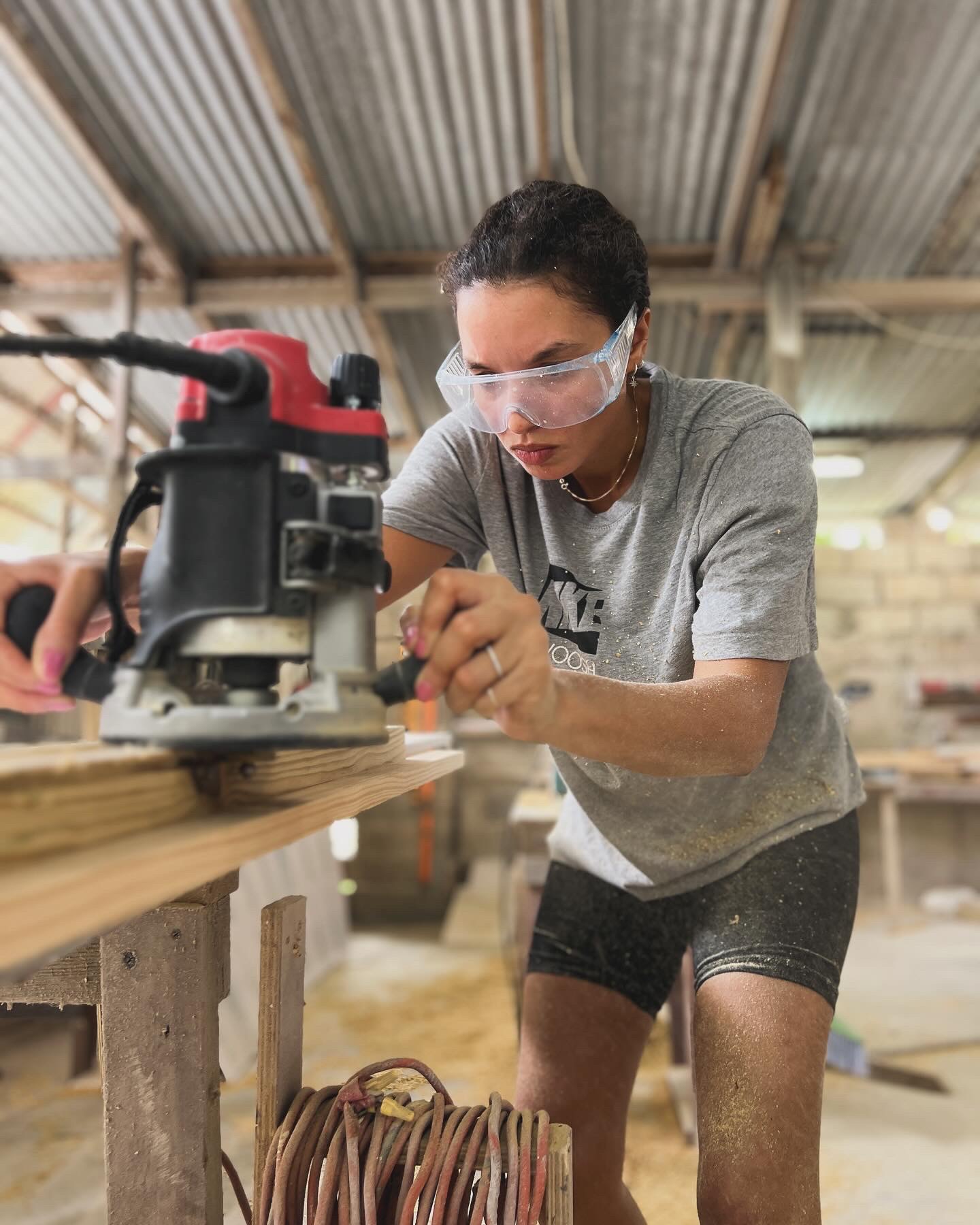 Akilah working with a wood router in the workshop